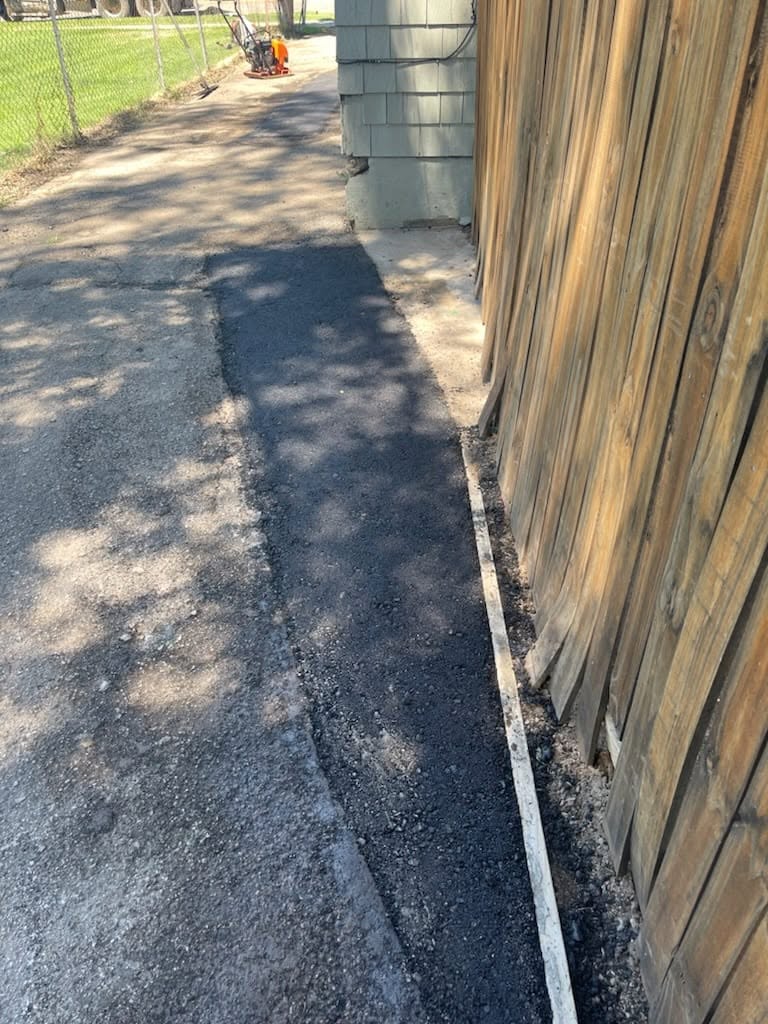 Asphalt edge repair alongside a fence
